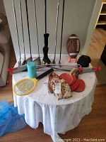 Full view of all items arranged on a round table, including golf clubs, Nike football, baseball glove, table tennis equipment, mosquito repeller and mosquito net.