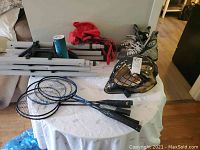 Wide angle photo showing badminton set pieces, rackets, skates, helmet on table.