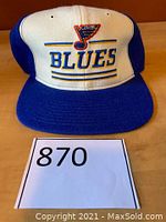 Front angle showing white front panel with embroidered St. Louis Blues logo and text 'BLUES' in blue and yellow, royal blue bill and side panels.