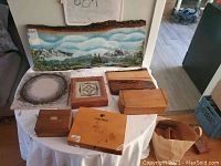 Overview of the collection on a table with multiple wood trinket boxes and the large wood slab painting behind.