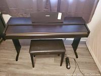 Front view of closed digital piano console with bench and pedal