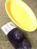 Yellow Fiesta Ware serving platter with eggplant salt and pepper shakers on eggplant tray.