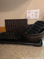 Photo showing multiple cast iron pieces on countertop including cornbread molds, grill plates, and stock pot.