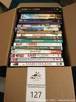 Photo of a box containing assorted DVD movies with visible titles and genres