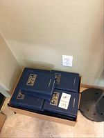 Top view of stacked blue hardcover hymnals titled 'Songs of the Church' in a cardboard box