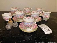 Overview of six cups with matching saucers, sugar bowl, creamer, three glass shakers