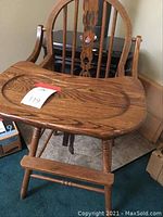 Full view of the wooden high chair showing the tray, backrest, and armrests.