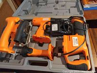 Set of cordless power tools including reciprocating saw, flashlight, drill, circular saw, charger and two batteries in carrying case.
