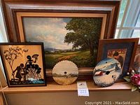 Wide view showing framed oil painting, vintage black paper silhouette, two painted saw blades with winter scenes