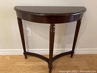 Front view of Bombay semi-circular accent table with three turned legs and smooth dark wood finish.