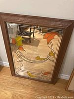 Front view of rectangular wooden framed mirror with stained glass floral design in orange and yellow