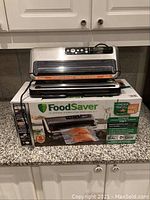 FoodSaver vacuum sealer on top of its product box, showing front view and control panel.