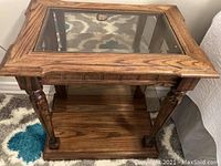 Front view of the vintage wooden side table with carved legs, glass inset top, and lower shelf