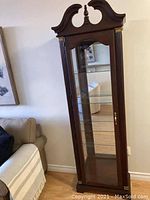 Full view of the vintage wooden display cabinet with ornate top and glass door.