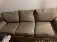 Front view of beige fabric couch with three seat cushions and three back cushions with visible stains and pen marks.