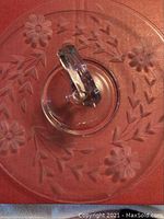 Top view of clear crystal platter showing floral etched design and faceted handle.