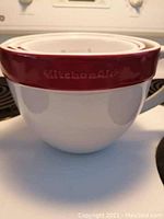 Close up of stacked KitchenAid ceramic measuring cups showing red rim and white interior