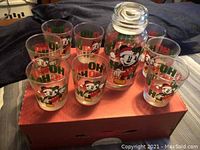 Top view of vintage Mickey Mouse glass set showing 8 glasses and cookie jar on a red box.
