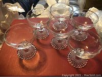 Five clear cocktail glasses displayed from side angle showing wide rounded bowls and dotted stems