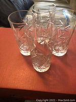 Four clear crystal drinking glasses with pinwheel cut patterns on a red surface.