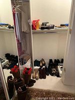Full closet view showing multiple pairs of shoes, boots and bags on shelf