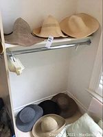 Seven ladies hats on shelf and floor in corner showing varieties of neutral colors and styles