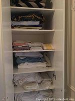 View of linens folded on shelves including towels, pillowcases, sheets, and mattress protector