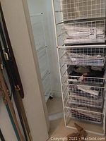 Wire shelving unit holding folded shirts and belts hung on side