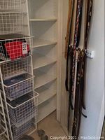 Wide view of wire shelving with multiple folded items in containers including shirts, with belts hanging vertically