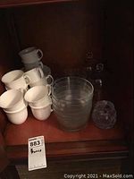 Set of white ceramic teacups stacked, clear glass bowls, and some other glassware.