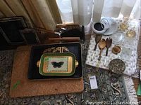Photo showing trays, cork pads, cleaning tools, and small kitchen items grouped on floor near curtains