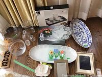 Photo showing ceramic platters, glass bowls, picture frames, decorative tray, and ceramic bunny plate on wooden floor