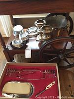 Photo of silverplate vases, coasters stacked, metal baskets on wooden tea cart