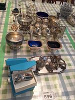 Wide shot of assorted silver-plated pieces on checkered tablecloth