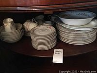 Assorted dishes including stacked dinner plates, bowls, teacups with saucers, various serving pieces