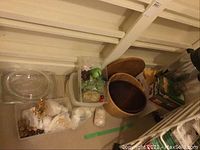 Wide view showing wooden bowls, cheese board, plastic bins with assorted items including decorations, and cardboard boxes.