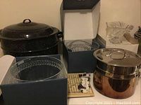 Wide view showing two boxed Villeroy & Boch glass bowls, black lobster pot, All-Clad pots, glass candy dish, and ceramic decor piece.