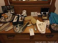 Overview of dresser top showing multiple silverplated trays, brushes, bookmarks and boxes