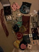 Overhead view of assorted costume jewelry on carpet including necklaces, bracelets, earrings, ring and watch