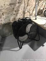 Black Lasko window fan with rectangular frame, dual blades, control buttons on top, placed on a concrete floor