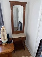 Full view of hallway mirror stand showing wood frame, mirror, brass hat hooks, stone top, single drawer, and lower shelf