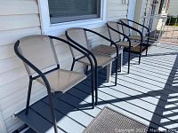 Four outdoor chairs with metal frames and beige mesh fabric seats and backs on a grey porch deck, showing design and condition.