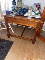 Full view of the rectangular wooden side table with carved accents and turned legs, showing surface wear.