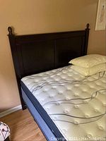 Photo showing queen size mattress and box-spring set with dark wood headboard.