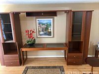 Front view of the 3-piece wooden entertainment unit with center table, showing glass doors and drawers on side cabinets and removable glass inserts on center table.