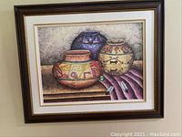 Framed art print showing three southwestern pottery vessels and feathers in earthy tones with dust visible on the frame and slight fading.