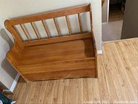 Full view of wooden bench showing the seat, armrests, and spindled backrest.