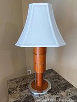 Side view of table lamp with white fabric shade and wooden segmented base showing condition and design details