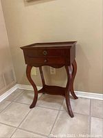 Wooden side table showing overall structure and curved legs.