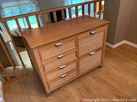 Front angled view showing top, drawers, and cupboard doors with wicker fronts and metal handles.